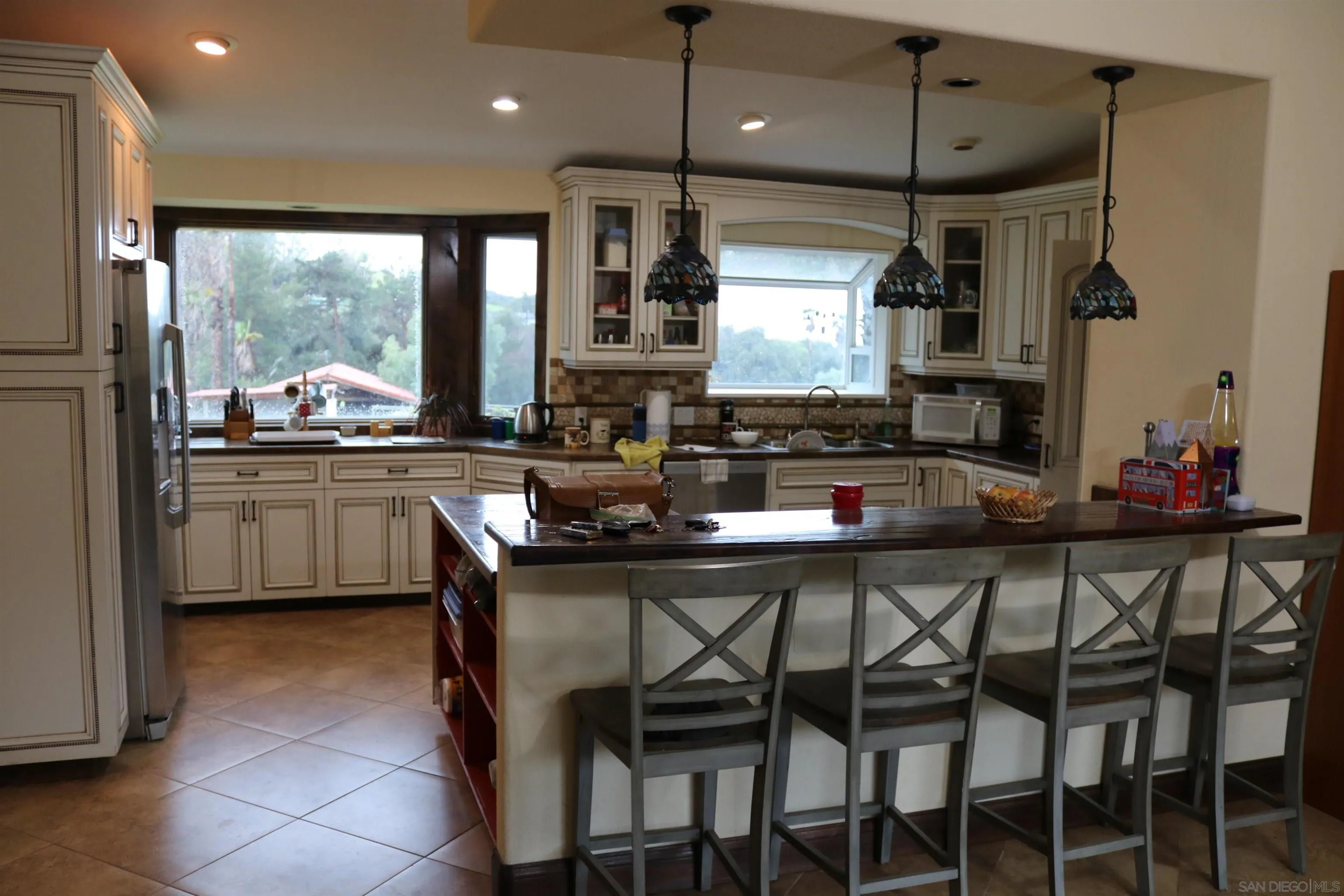 38083 De Luz Road Fallbrook, CA 92028 - Photo 11 of 29 a kitchen with stainless steel appliances a dining table chairs sink and white cabinets