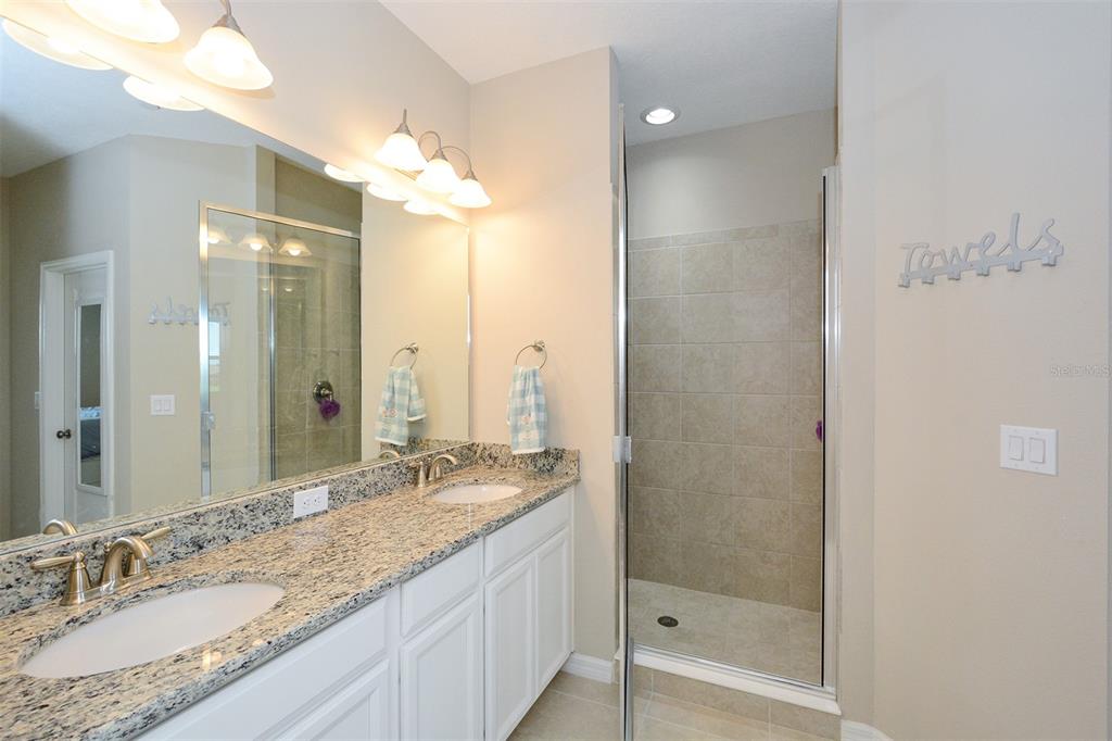 13737 Messina Loop, Unit 202 Lakewood Ranch, FL 34211 - Photo 27 of 49 a bathroom with a granite countertop sink a mirror and a shower