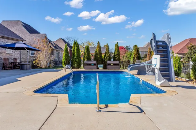 a view of a swimming pool with a bench and trees in the background