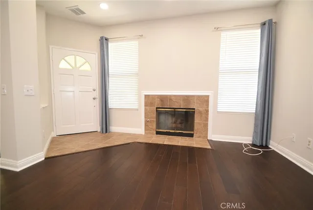 an empty room with wooden floor a fireplace and windows