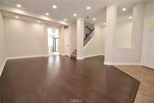 a view of an empty room with wooden floor and stairs