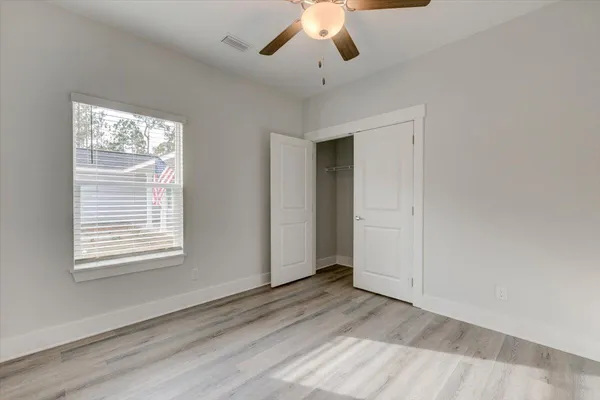 a view of empty room with wooden floor and fan