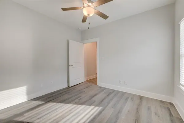 an empty room with wooden floor chandelier fan and closet area