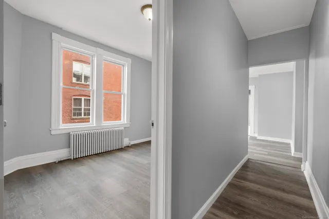 a view of an empty room with wooden floor and a window