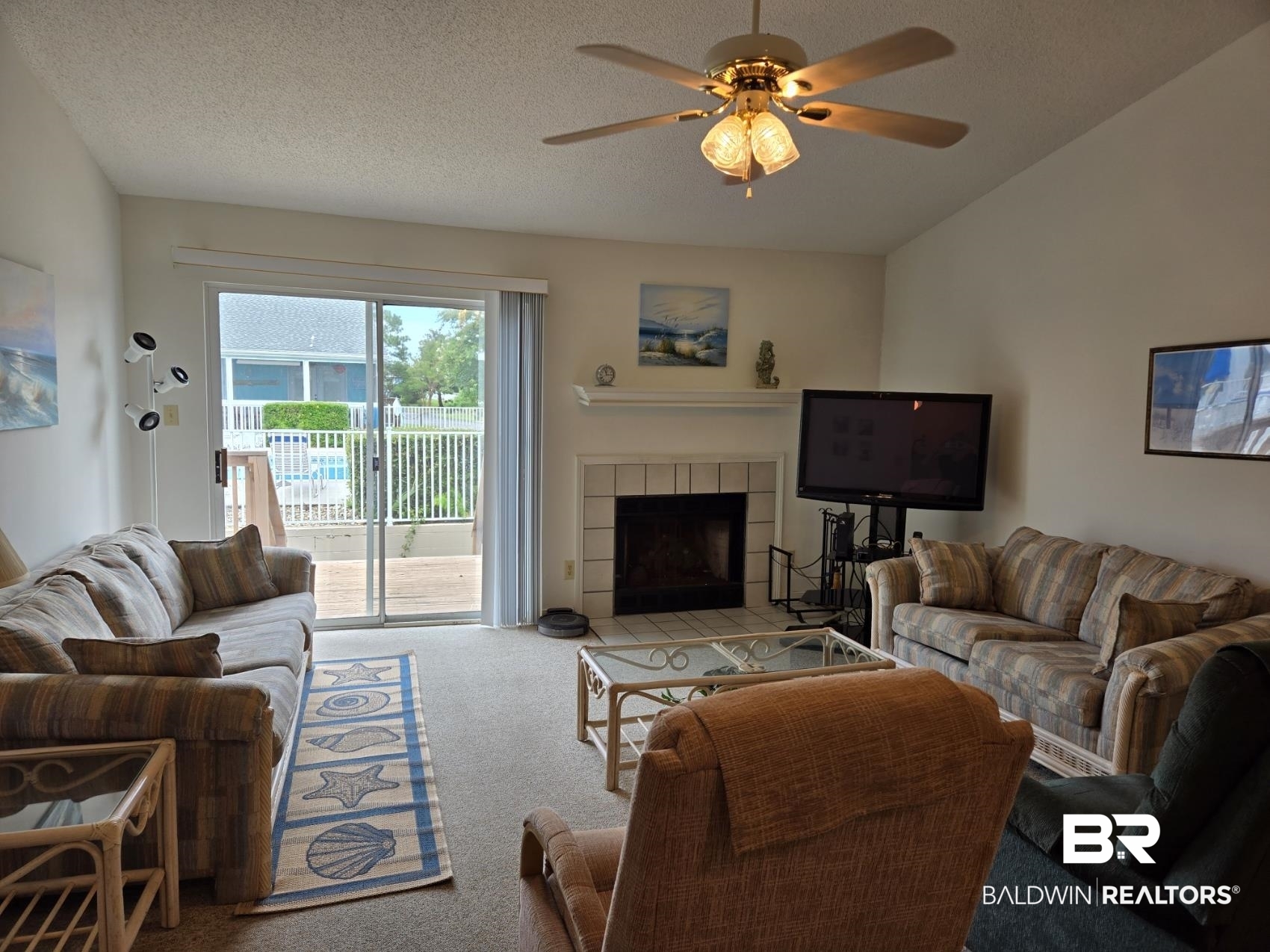 3200 Loop Road, Unit 87 Orange Beach, AL 36561 - Photo 2 of 46 Living room with a textured ceiling, vaulted ceiling, ceiling fan, a tiled fireplace, and carpet