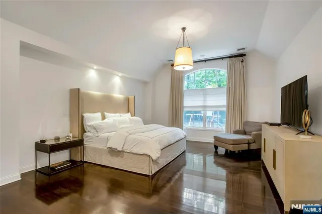 a spacious bedroom with a bed and a flat screen tv