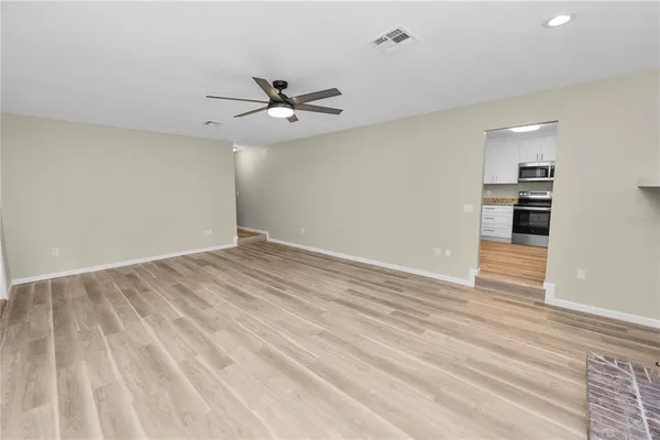 a view of empty room with wooden floor and fan