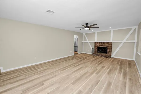 an empty room with a ceiling fan and a fireplace