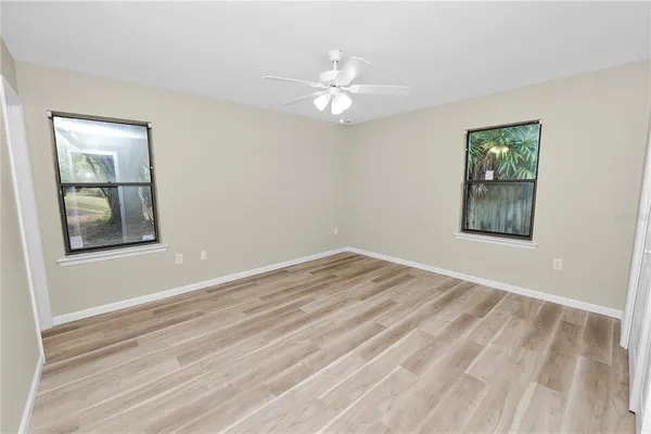 a view of an empty room with window and wooden floor