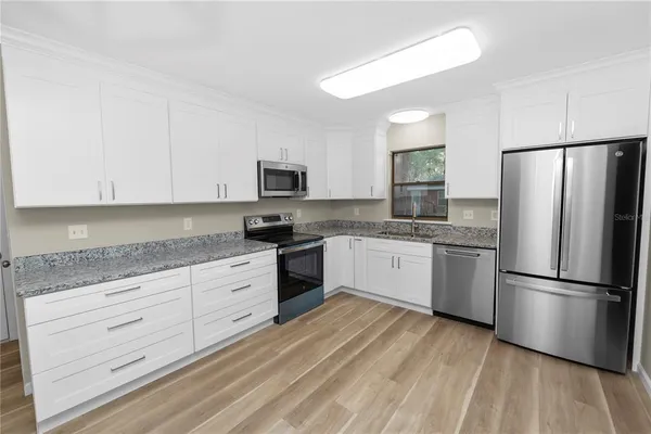 a kitchen with granite countertop white cabinets and stainless steel appliances