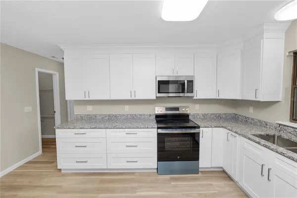 a kitchen with granite countertop white cabinets and stainless steel appliances