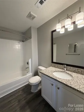 a bathroom with a granite countertop sink a toilet a mirror and bathtub