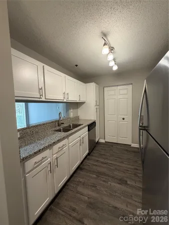 a kitchen with granite countertop a refrigerator and a sink