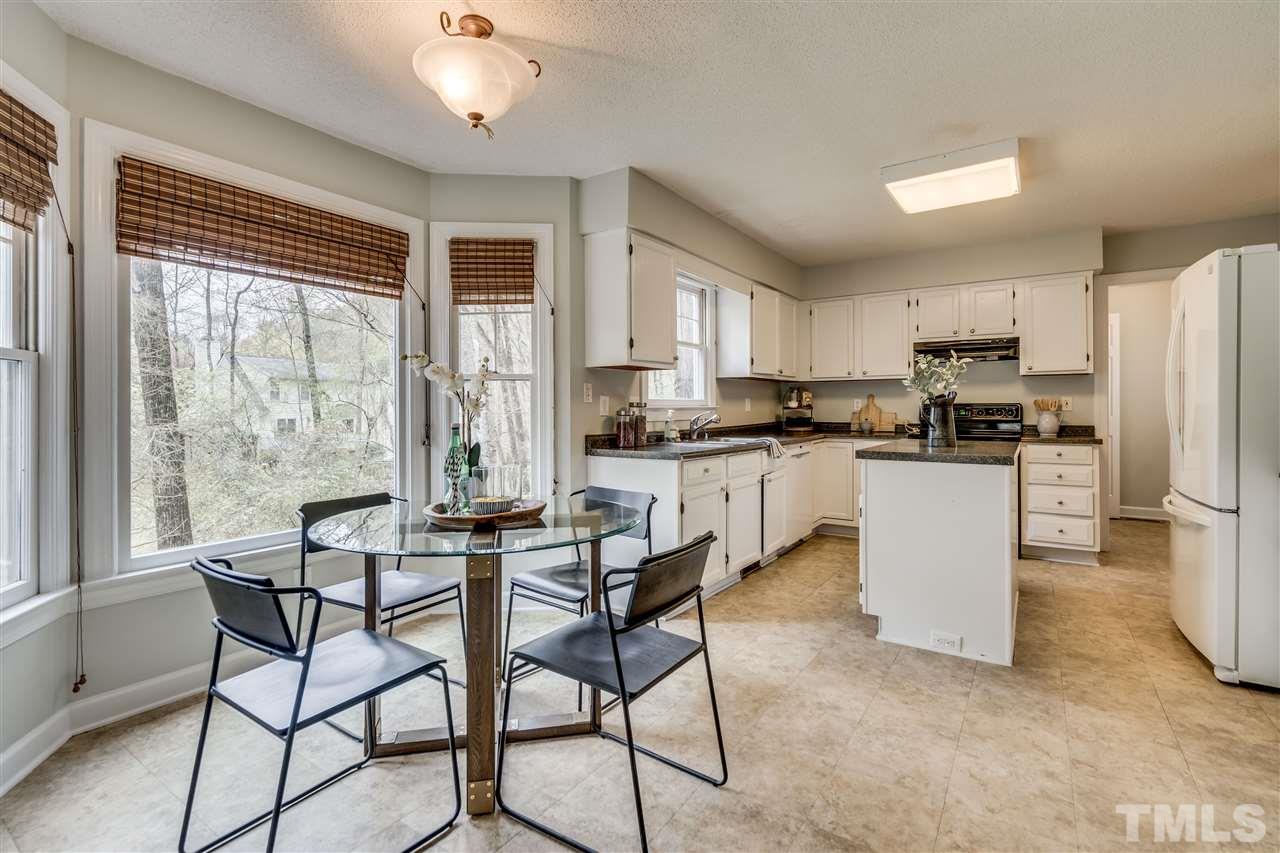 1 Swallows Ridge Court Durham, NC 27713 - Photo 13 of 26 a kitchen with stainless steel appliances granite countertop a stove a refrigerator a sink a dining table and chairs with wooden floor