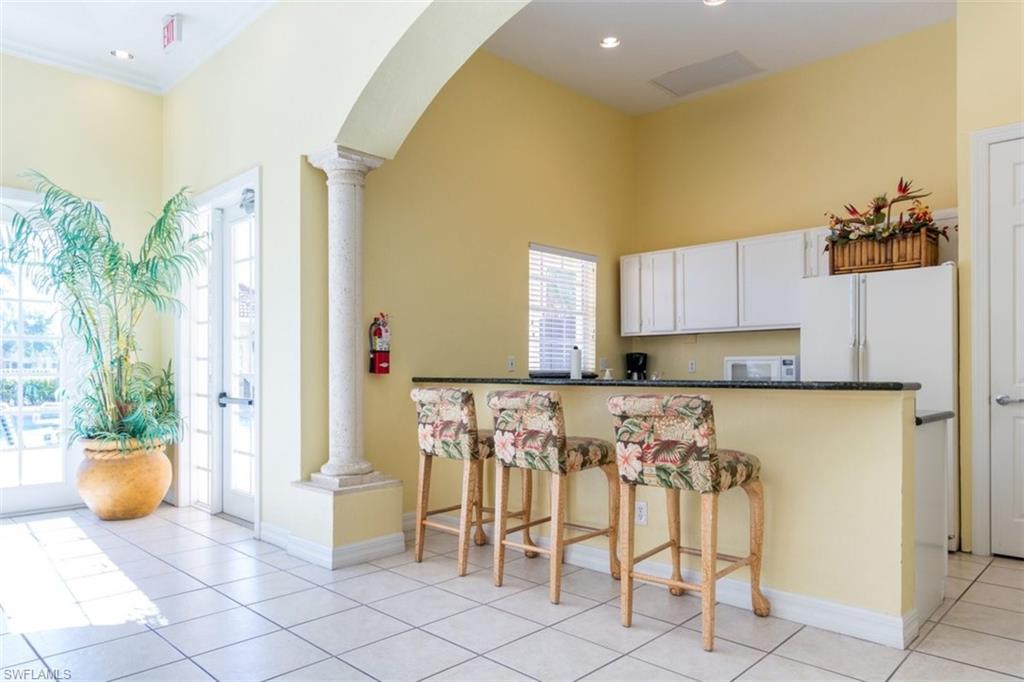 4635 St Croix Lane, Unit 1218 Naples, FL 34109 - Photo 31 of 40 Kitchen with decorative columns, white appliances, healthy amount of natural light, a towering ceiling, and recessed lighting