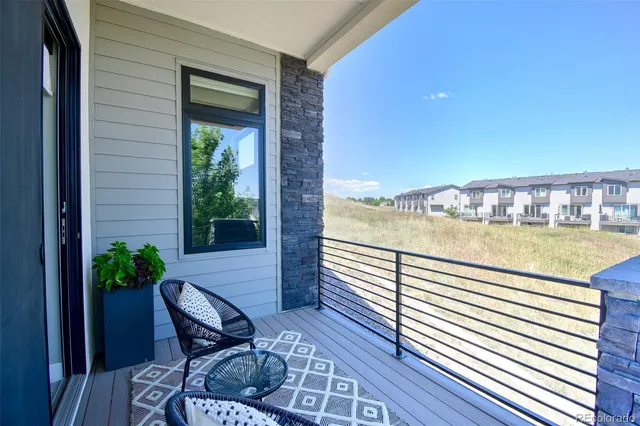 a balcony with chairs and with potted plants