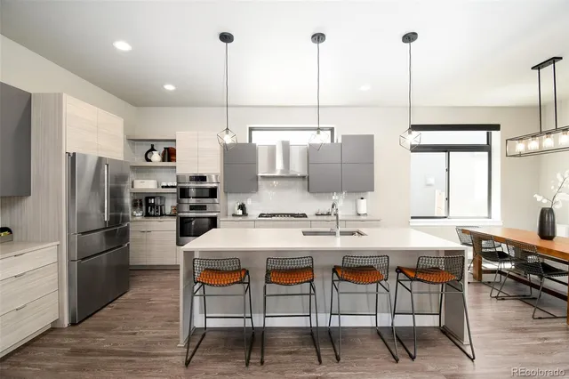 a kitchen with stainless steel appliances kitchen island granite countertop a table chairs and a refrigerator
