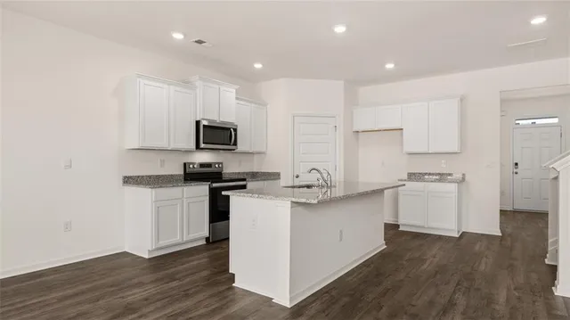 a kitchen with granite countertop white cabinets and stainless steel appliances