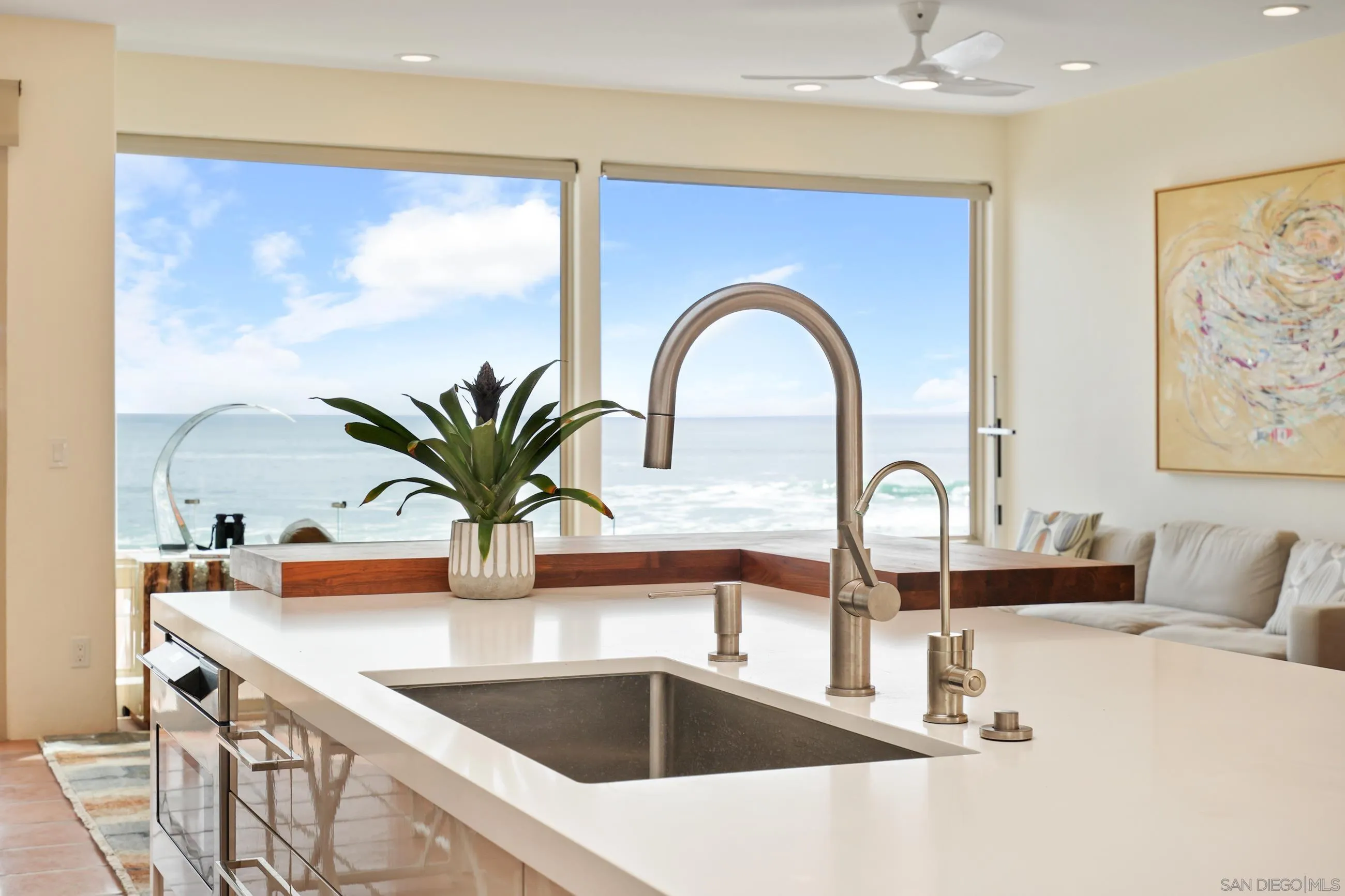 5650 Dolphin Place La Jolla, CA 92037 - Photo 11 of 54 a kitchen with a faucet a sink and a dining table with a potted plant
