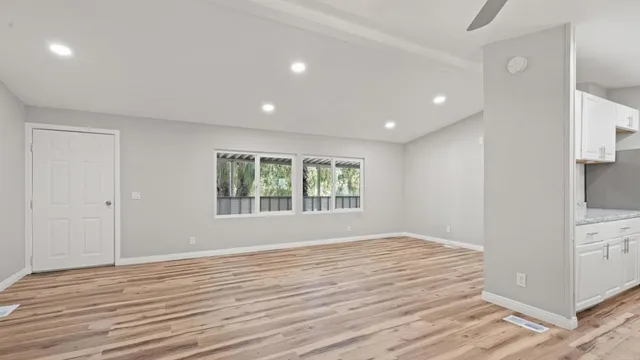 a view of empty room with wooden floor and fan