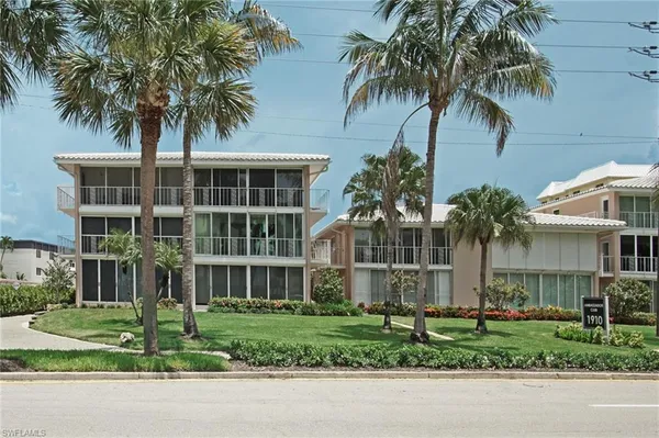 a front view of a house with a garden and palm trees