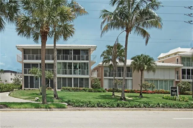 a front view of a house with a garden and palm trees
