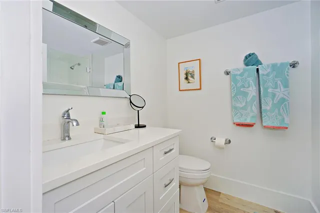 a bathroom with a granite countertop toilet sink and mirror