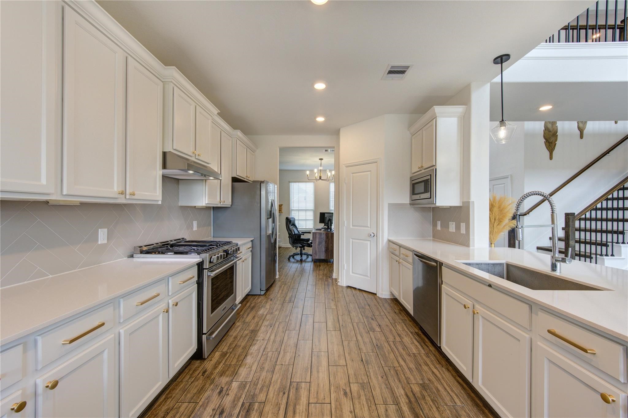 a large kitchen with stainless steel appliances granite countertop a lot of counter space and wooden floors