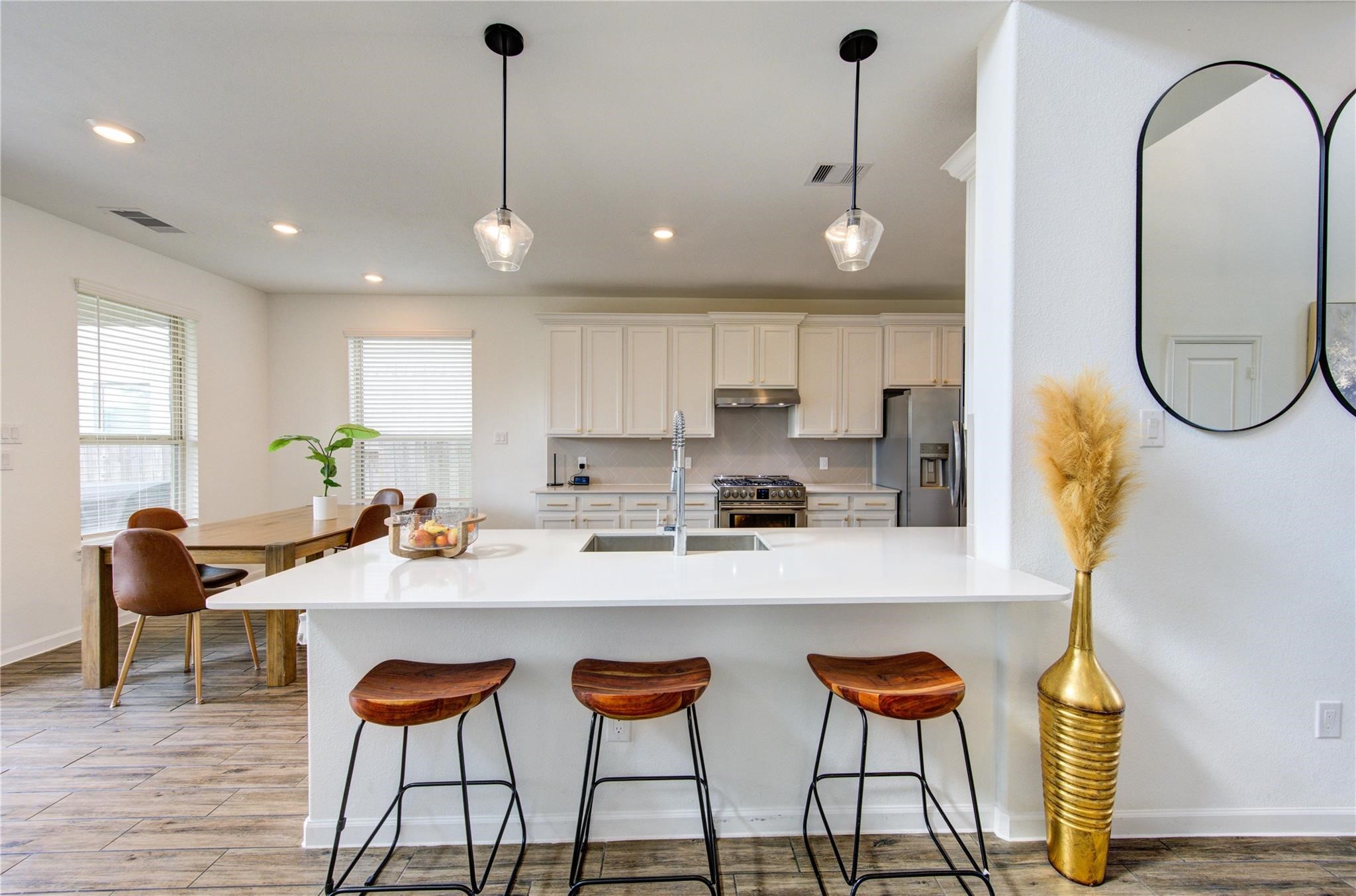 17530 Sunset Skies Road Conroe, TX 77302 - Photo 14 of 47 a kitchen with stainless steel appliances granite countertop a sink a stove a refrigerator and chairs with wooden floor