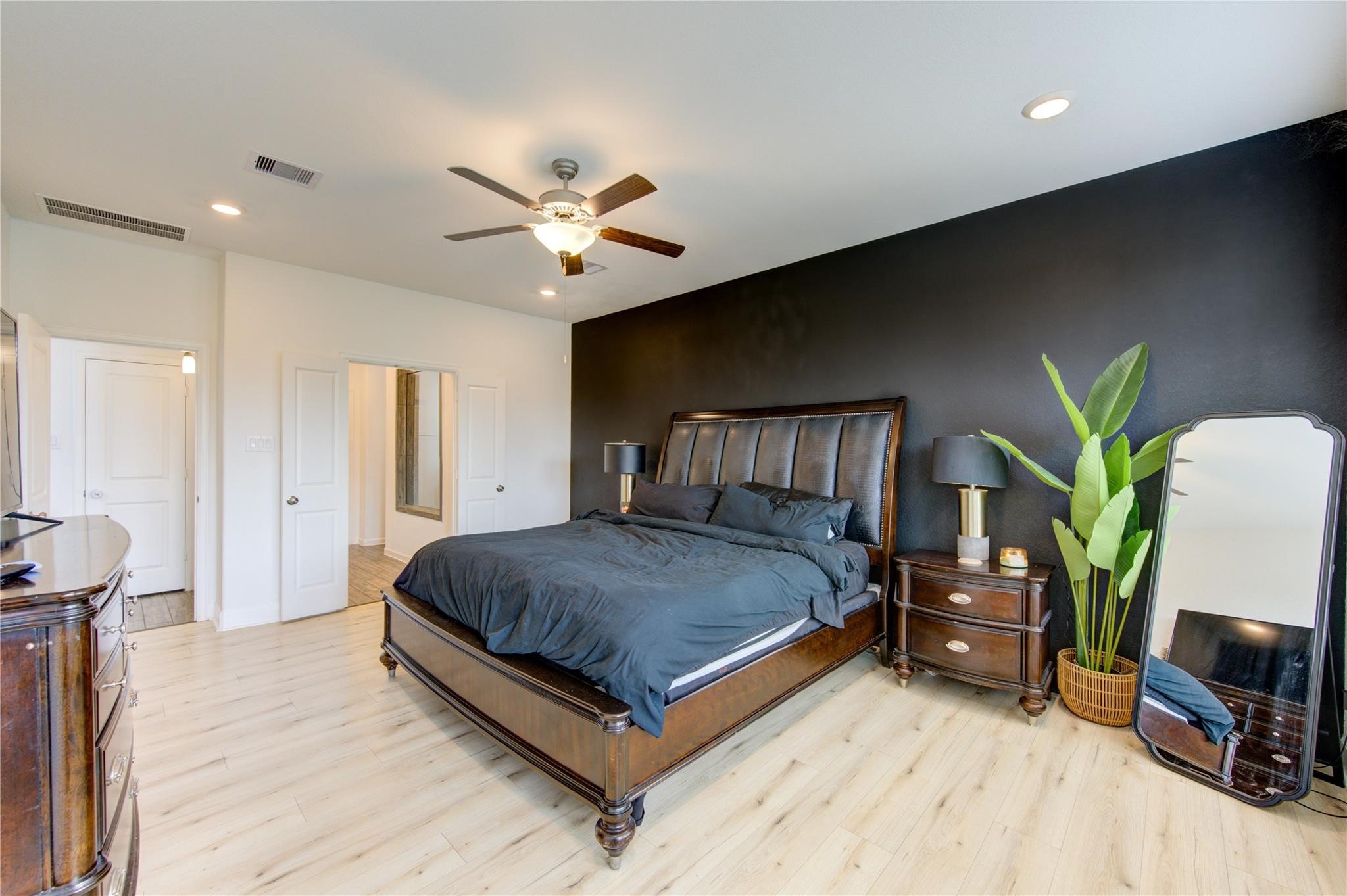 17530 Sunset Skies Road Conroe, TX 77302 - Photo 23 of 47 a spacious bedroom with a bed a couch and a potted plant on the dresser