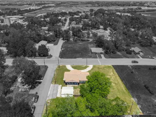 an aerial view of residential houses with outdoor space and trees