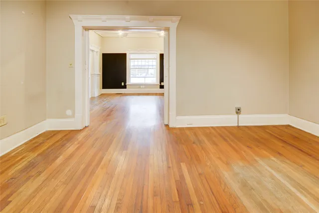 a view of a hallway with wooden floor and a bathroom