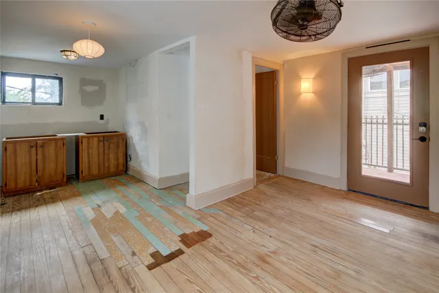 a view of an empty room with a window and wooden floor
