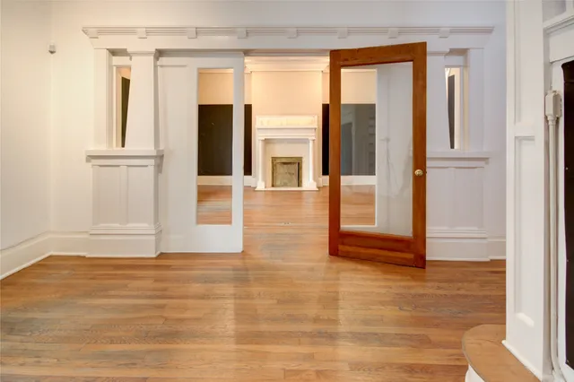a view of an empty room with wooden floor and a window