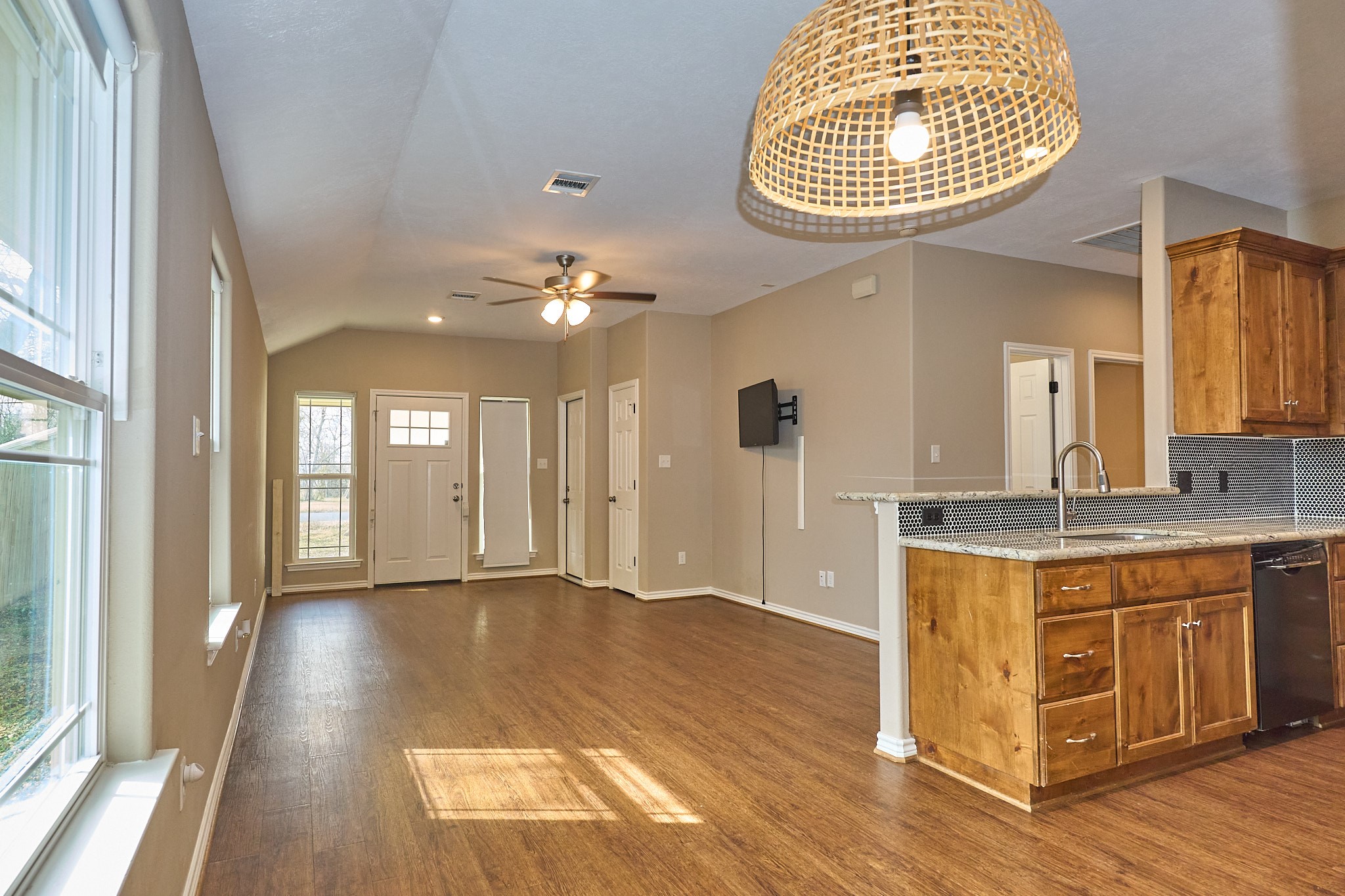 1807 Nuches Lane Bryan, TX 77803 - Photo 1 of 27 Bright and open living space with hardwood floors, modern kitchen featuring granite countertops and wooden cabinets, large windows, and a stylish light fixture. Ideal for comfortable living and entertaining.