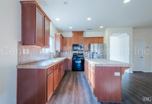 a kitchen with stainless steel appliances granite countertop wooden cabinets a stove top oven a sink and dishwasher