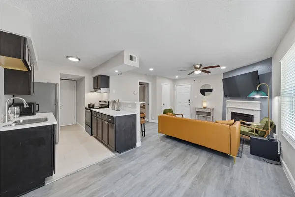 a large white kitchen with stainless steel appliances granite countertop a stove oven a sink dishwasher and a fireplace with wooden floor