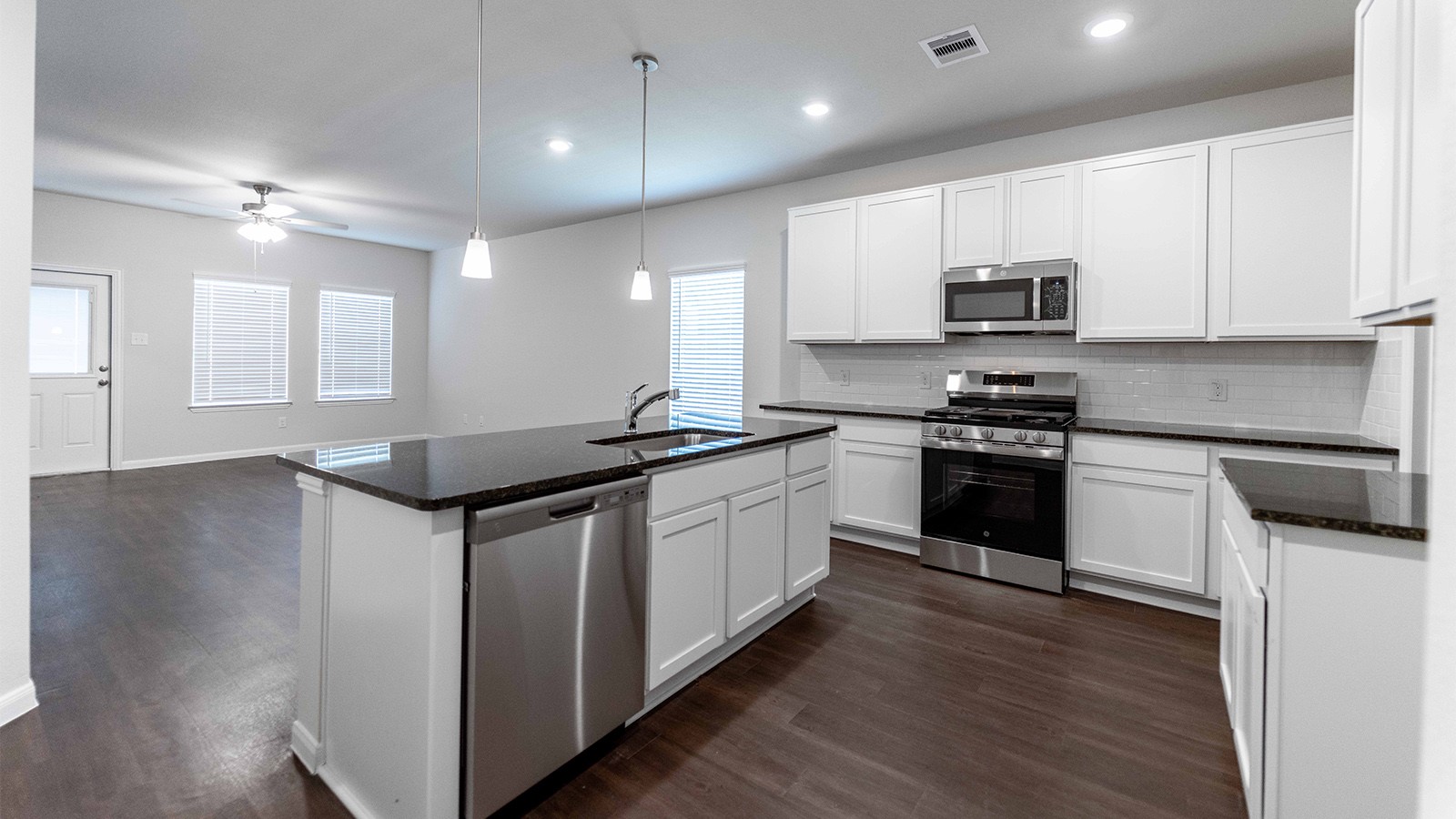 1539 Windrose Bend Angleton, TX 77515 - Photo 4 of 13 a kitchen with stainless steel appliances a sink a stove a microwave a center island and a window
