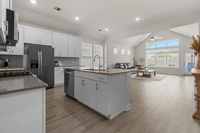 a kitchen with stainless steel appliances a refrigerator a stove a sink dishwasher and a refrigerator with wooden floor