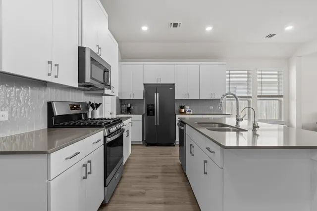 a large kitchen with stainless steel appliances granite countertop a stove a sink and a refrigerator