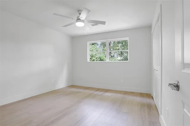 an empty room with windows and fan