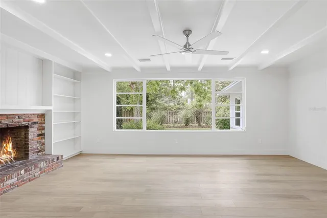 an empty room with windows fireplace and fan