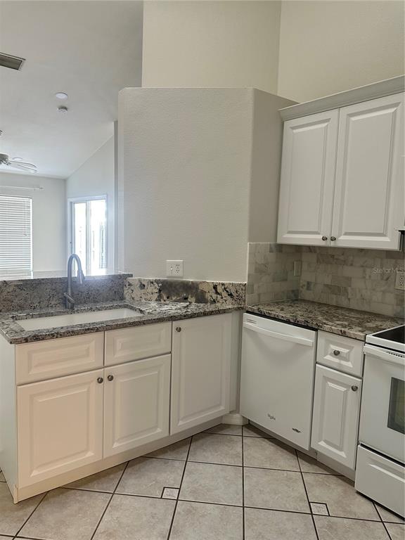 658 Green Valley Road, Unit B3 Palm Harbor, FL 34683 - Photo 6 of 24 a kitchen with granite countertop white cabinets