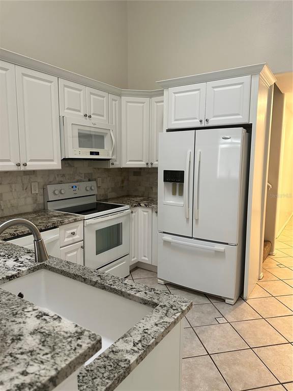 658 Green Valley Road, Unit B3 Palm Harbor, FL 34683 - Photo 7 of 24 a kitchen with a refrigerator stove and white cabinets