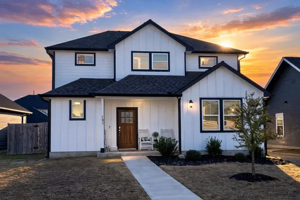 a front view of house with yard and trees in the background
