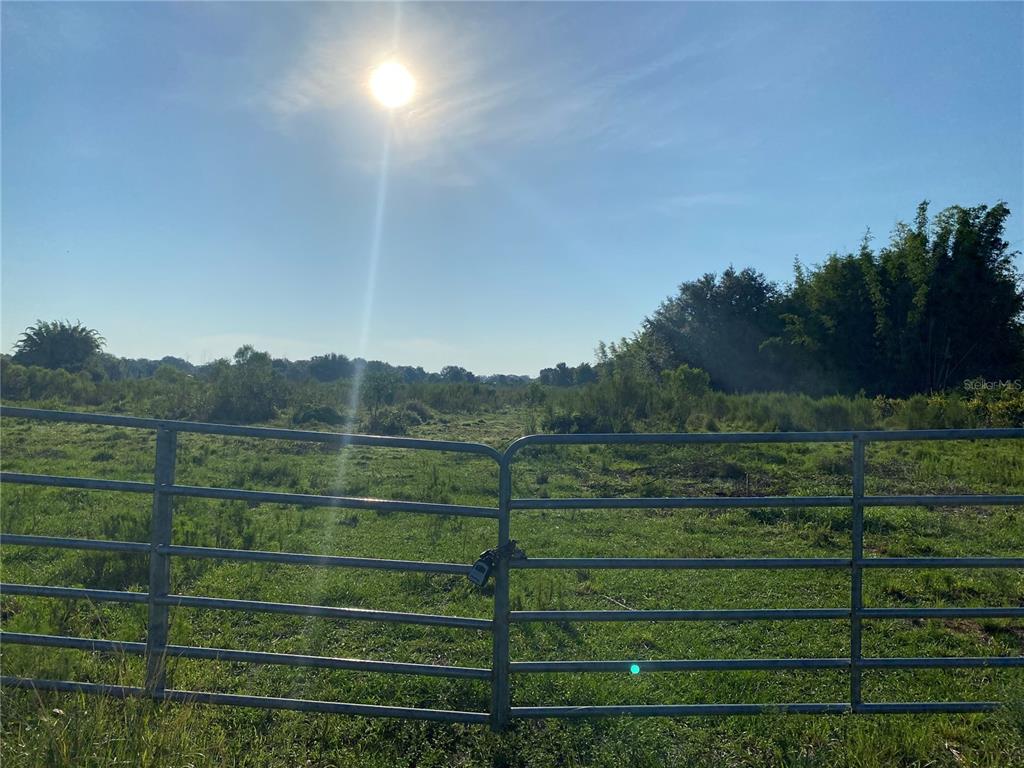 5187 Greenfields Run Zolfo Springs, FL 33890 - Photo 2 of 8 a view of a green field with a wooden fence