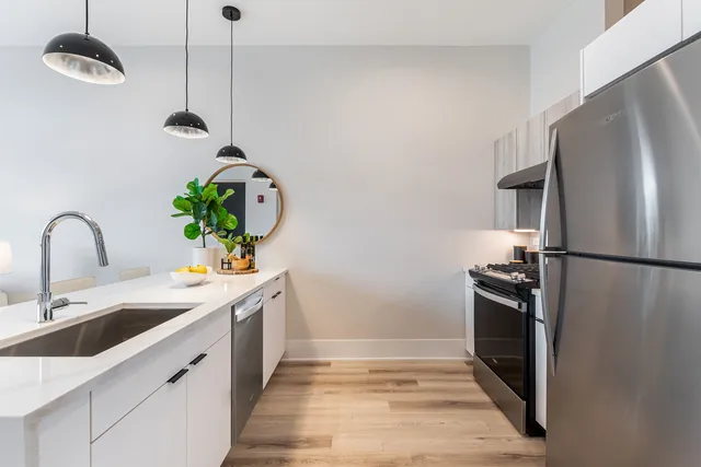 a kitchen with stainless steel appliances a sink a refrigerator a stove a chimney and wooden floor