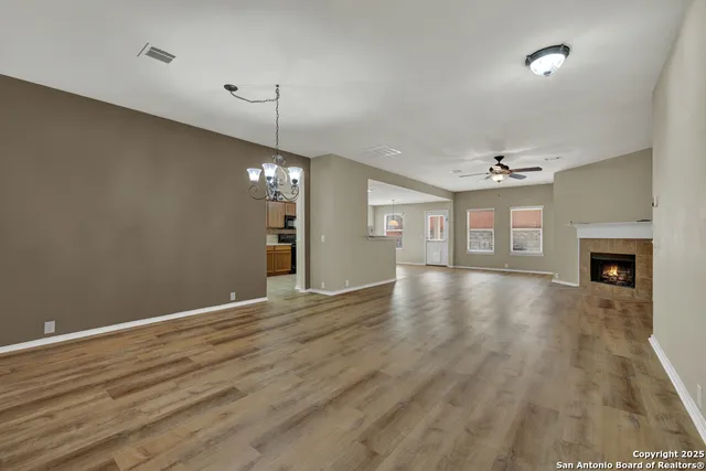 a view of an empty room with wooden floor and a fireplace