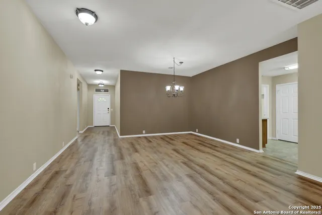 an empty room with wooden floor and chandelier