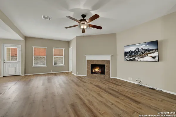 a view of an empty room with wooden floor fireplace and a window
